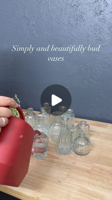 a woman is pouring water into her glass vases on a wooden table with the words simply and beautifully budi