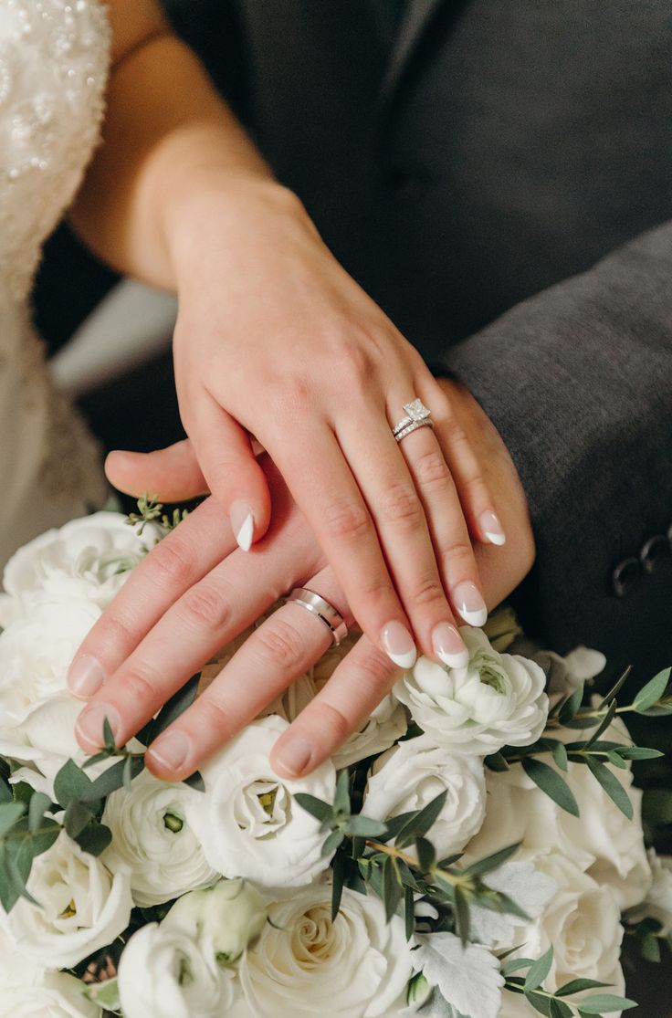 the bride and groom are holding hands with their wedding rings