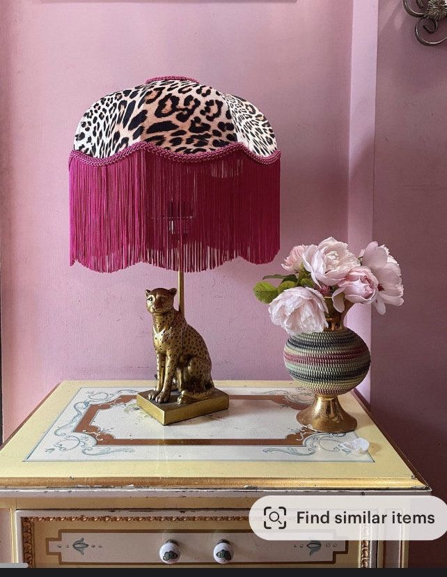 a lamp that is sitting on top of a table next to a vase with flowers