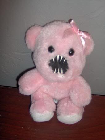 a pink teddy bear with big teeth on it's face sitting on a table