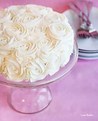 a cake with white frosting sitting on top of a pink tablecloth covered table