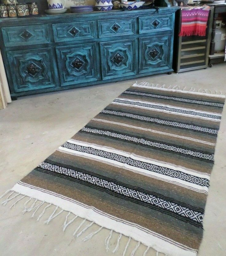 a large rug sitting on top of a white floor next to a dresser and drawers