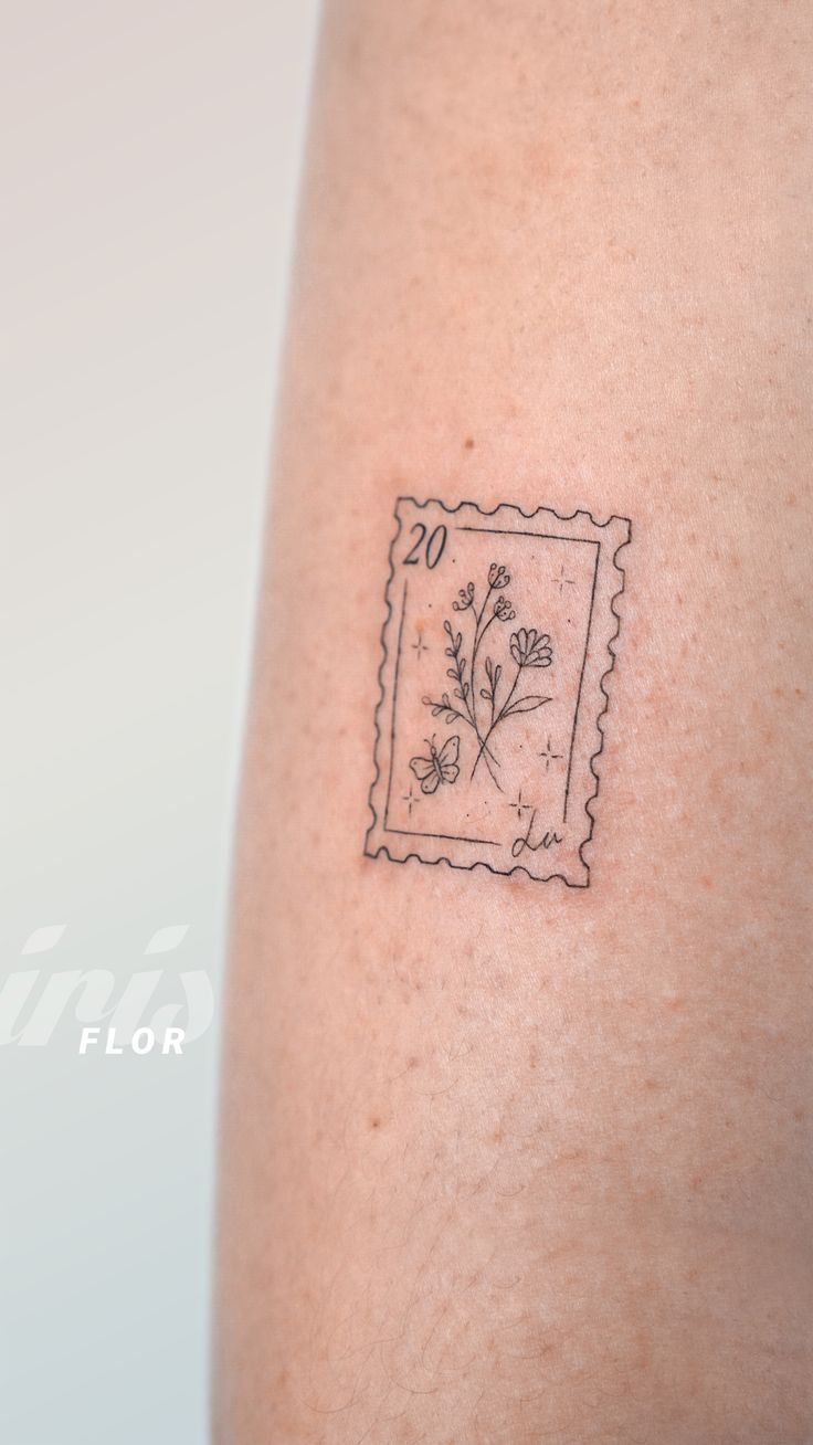 a small stamp with flowers on the back of a woman's arm that is covered in black ink