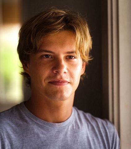 a close up of a person wearing a gray shirt and looking at the camera with a serious look on his face