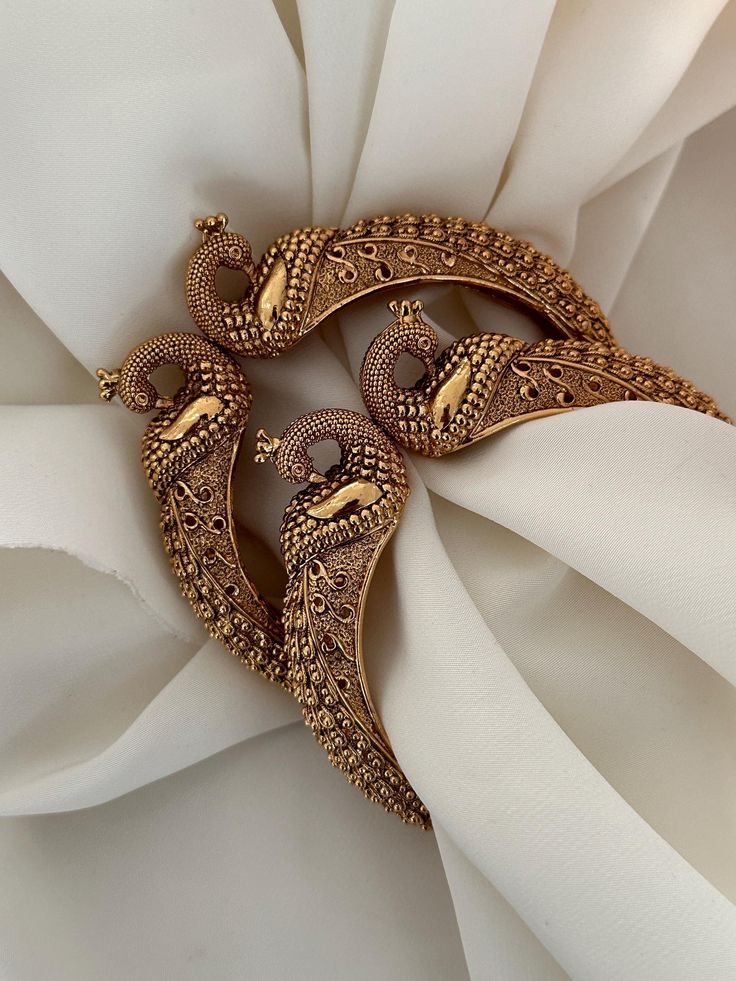 Antique gold finish peacock design kada. Amazing detailing.  clutches on wrist, not screw, easy to wear( set of 2) Style tip- Pair it with any beautiful traditional outfits  and flaunt with Unique style of collection from us. Perfect match for Festival and Traditional wear.  Take Care Tips-  Kee away from perfume, Hair spray and. Moisture.  Store in dry place , Ziplock bag or Airtight box.    Clean with dry cloth.  Jewellery is the last thing you should wear and first thing you should remove.  - Luxury Chandbalis With Peacock Design For Wedding, Elegant Chandbalis With Intricate Design For Puja, Elegant Chandbalis For Puja With Intricate Design, Ceremonial Gold Chandbalis With Peacock Design, Gold Jewelry With Peacock Design For Diwali, Gold Chandbalis With Peacock Design For Ceremonial Events, Gold Chandbalis With Peacock Design For Ceremonial Occasions, Gold Jewelry With Peacock Design For Festivals, Elegant Chandbalis With Peacock Design For Diwali