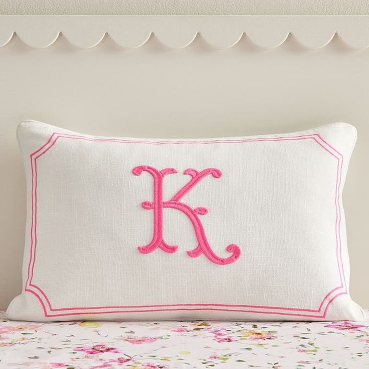 a pillow with the letter k on it sitting on top of a floral print bed