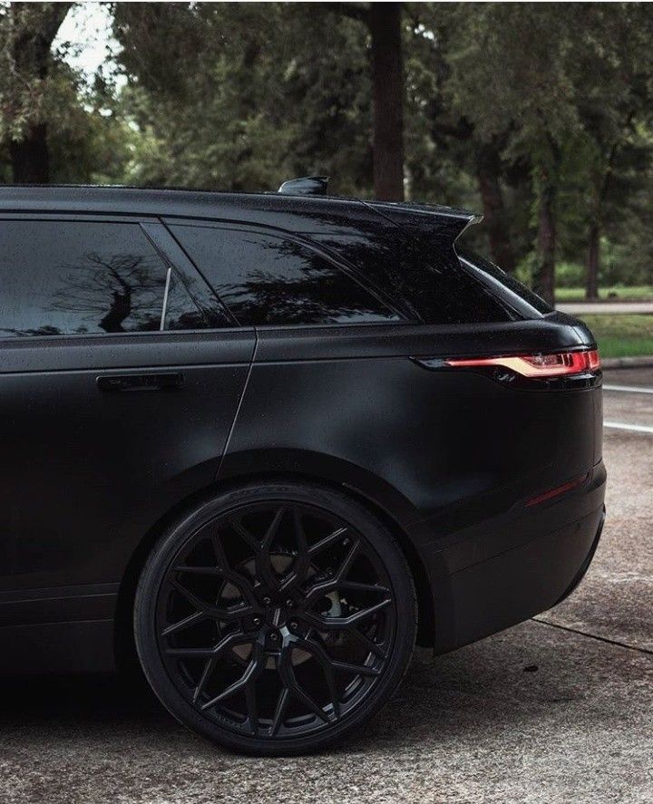 the black range rover is parked in front of some trees