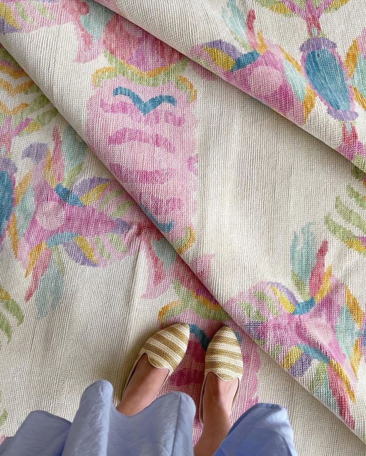 a pair of shoes sitting on top of a bed next to a flowered blanket