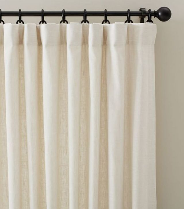 a white curtain with black metal rods hanging from it's side in front of a window