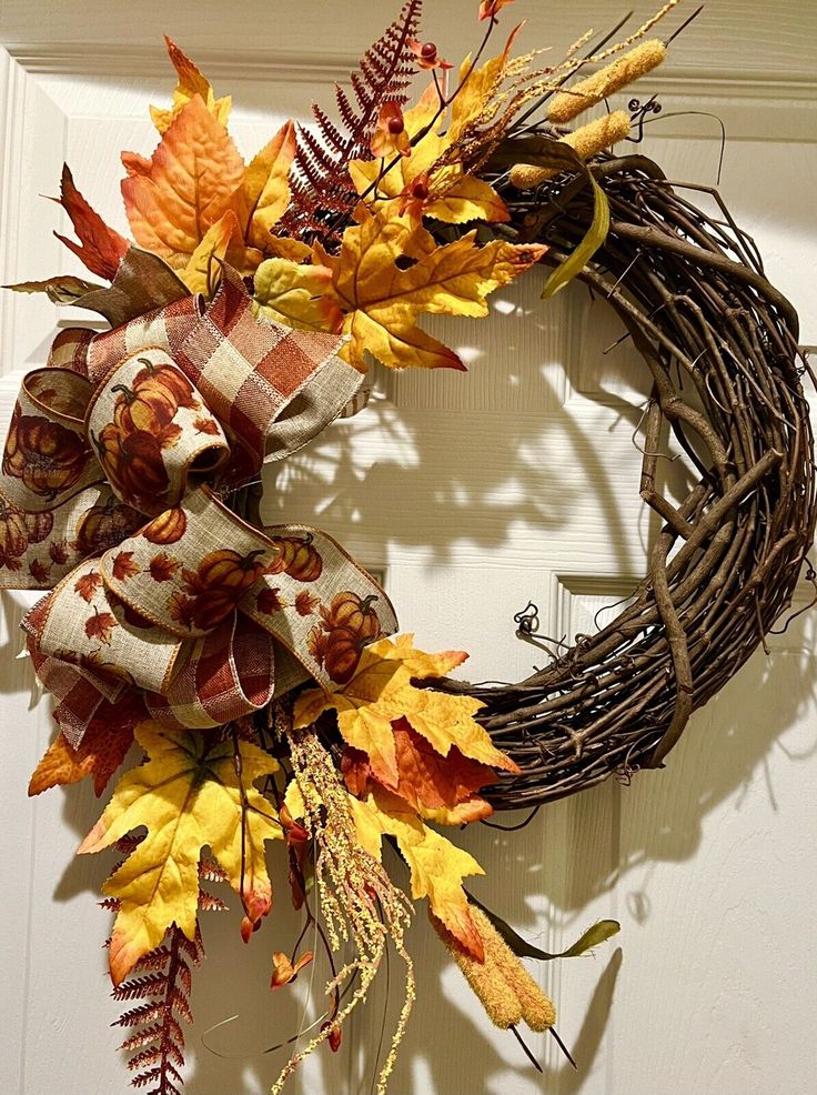 a wreath with fall leaves on the front door