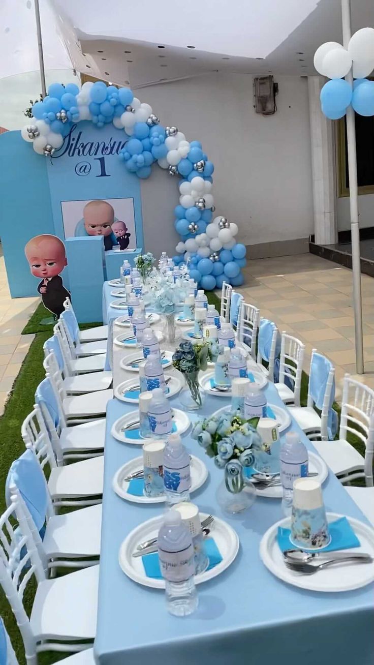 a table set up for a baby shower party with blue and white decorations on it