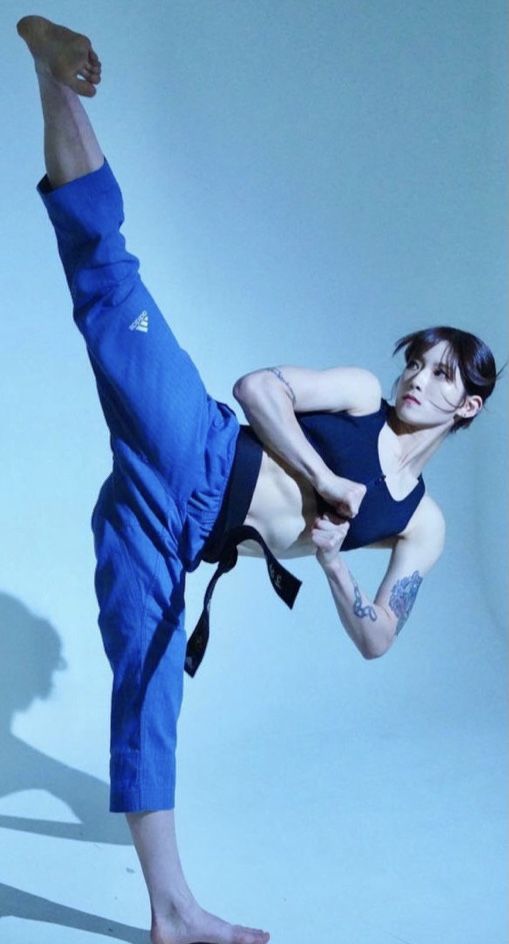 a woman in blue pants doing a kickbox pose with one leg on the ground