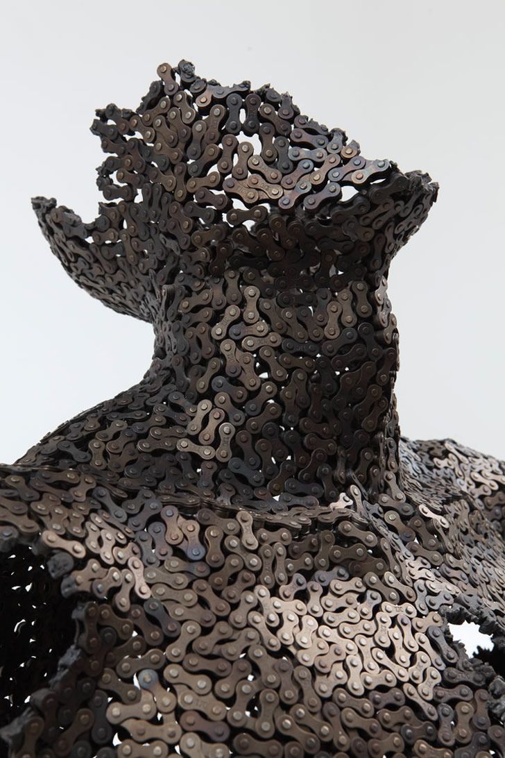 a sculpture made out of metal discs on top of a white surface with no one around it