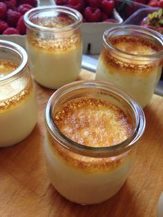 four jars filled with pudding sitting on top of a wooden table