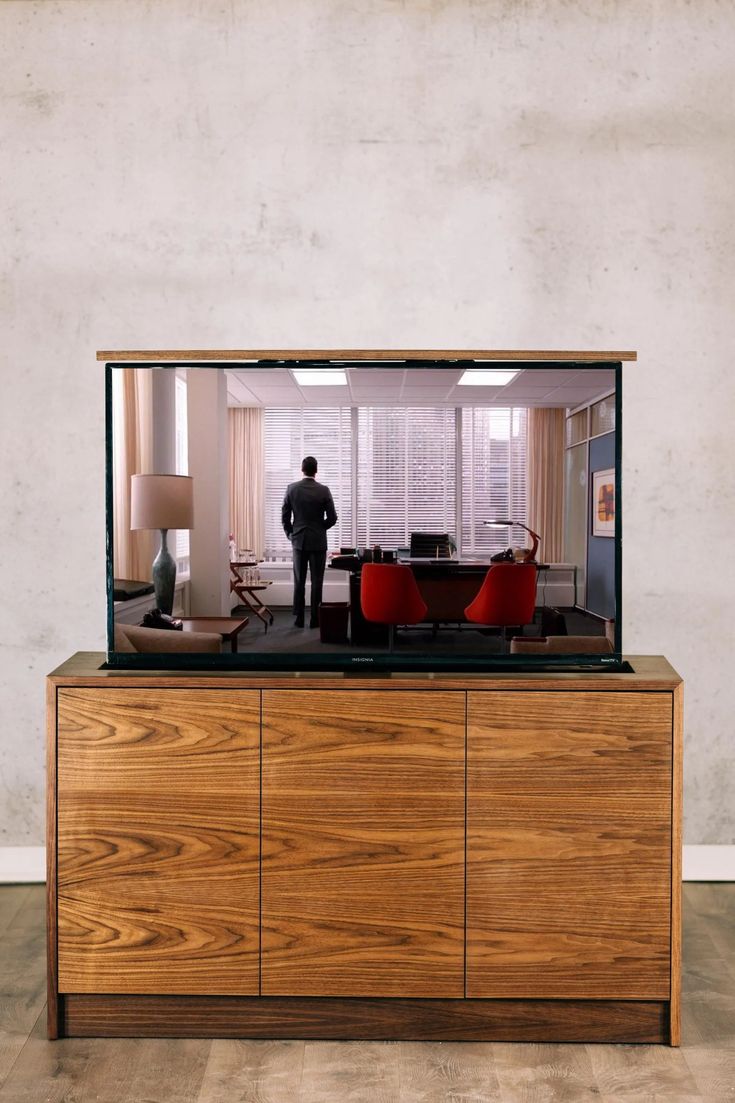 a man standing in the middle of a living room with a tv on top of it