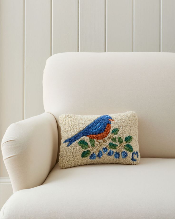 a white chair with a blue and red bird pillow on it