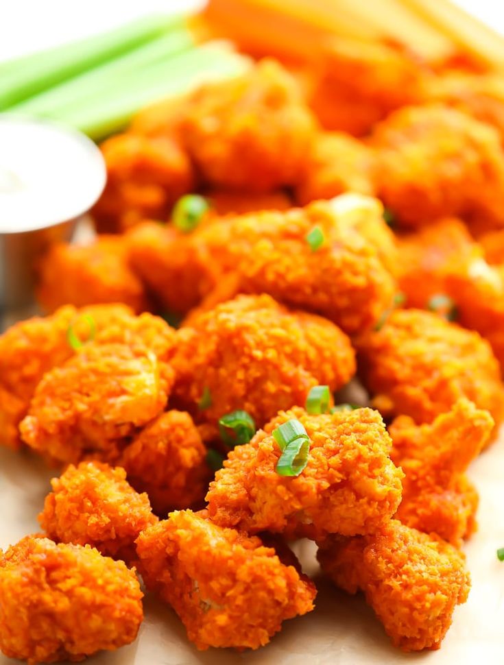 some fried food on a white plate with green onions and carrots next to it