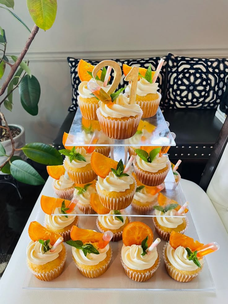 cupcakes with white frosting and orange flowers are arranged on a cake stand