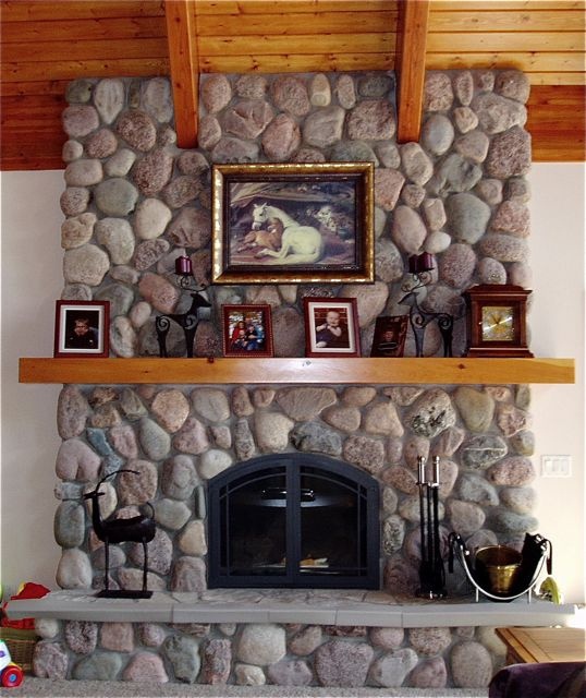 a stone fireplace with pictures on the mantle