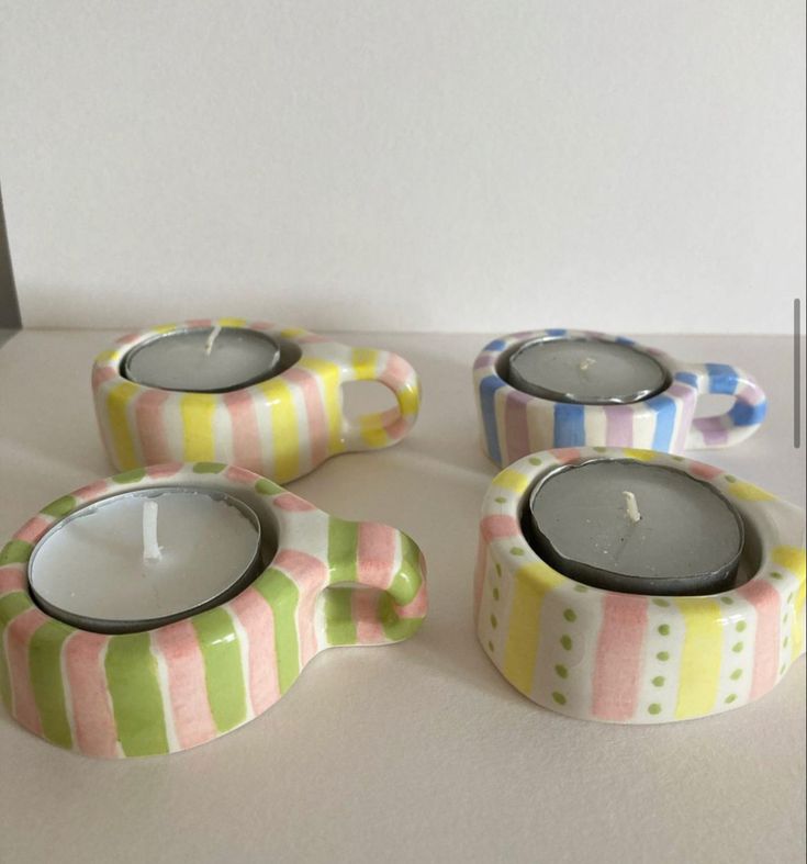 three candles sitting on top of a table next to each other with different designs and colors