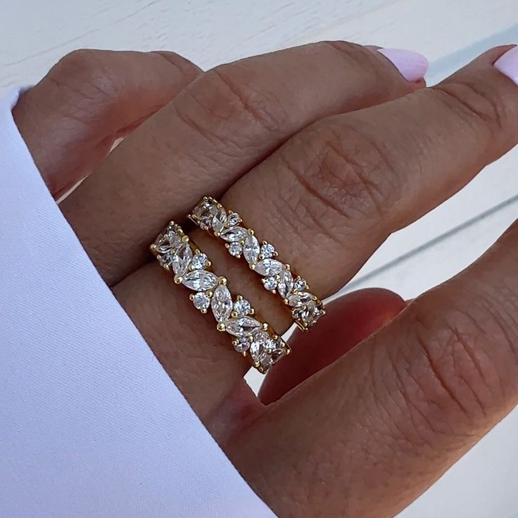 a woman's hand with two gold rings on it and one diamond ring in the middle