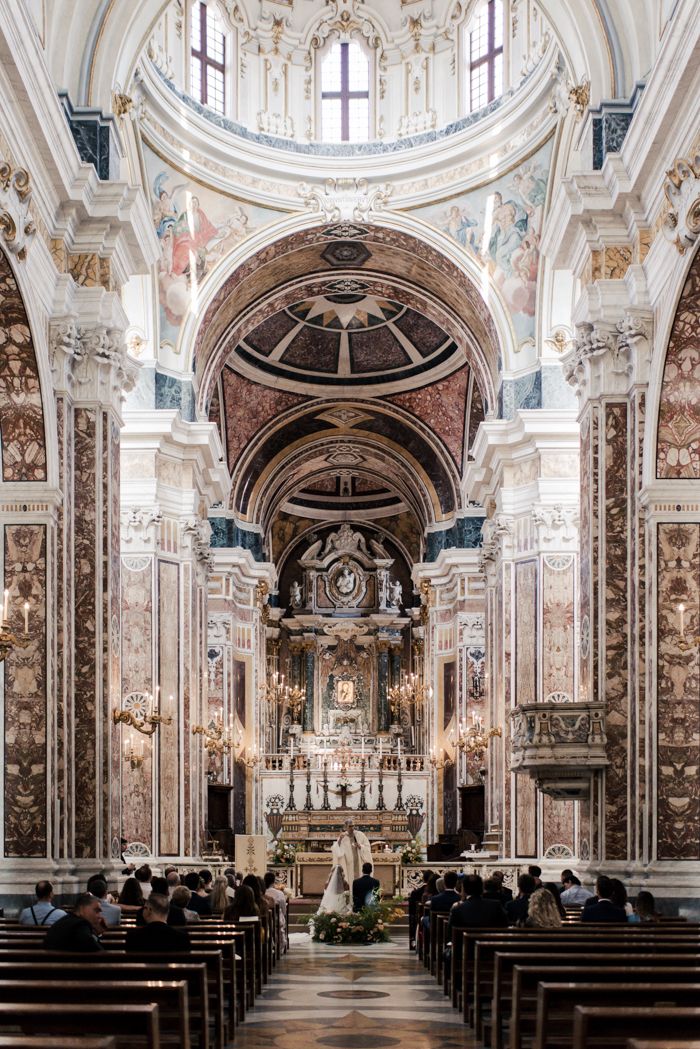 the inside of a church with pews and people sitting at it's alter