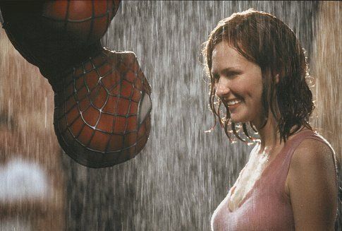 a woman standing in the rain next to a spider man