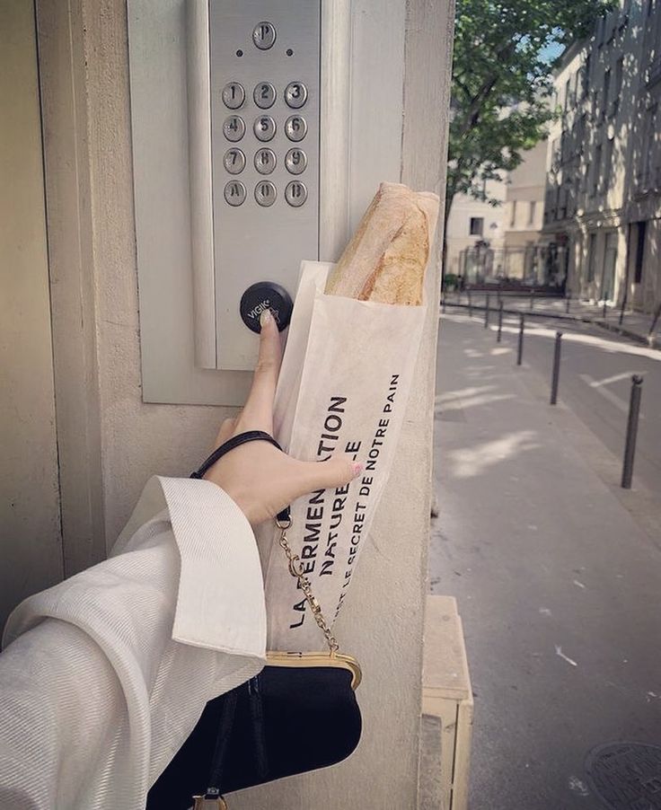 a person is holding a baguette in front of an atm machine on the street