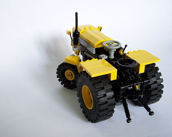 there is a lego tractor on the white surface with yellow wheels and black rims