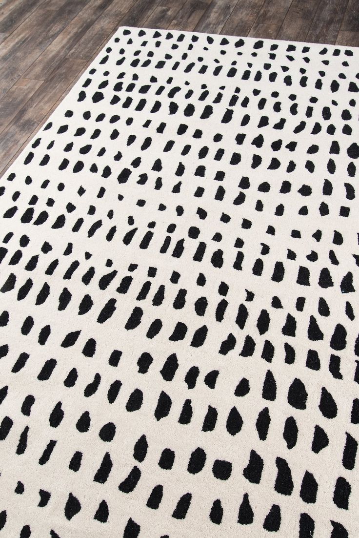 a black and white area rug with spots on the floor in front of a wooden floor