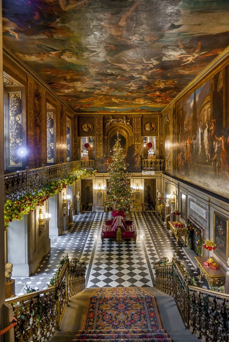 an ornately decorated room with a christmas tree in the center and paintings on the walls