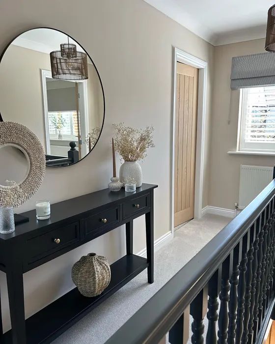 a hallway with a table, mirror and vases on the railing next to it