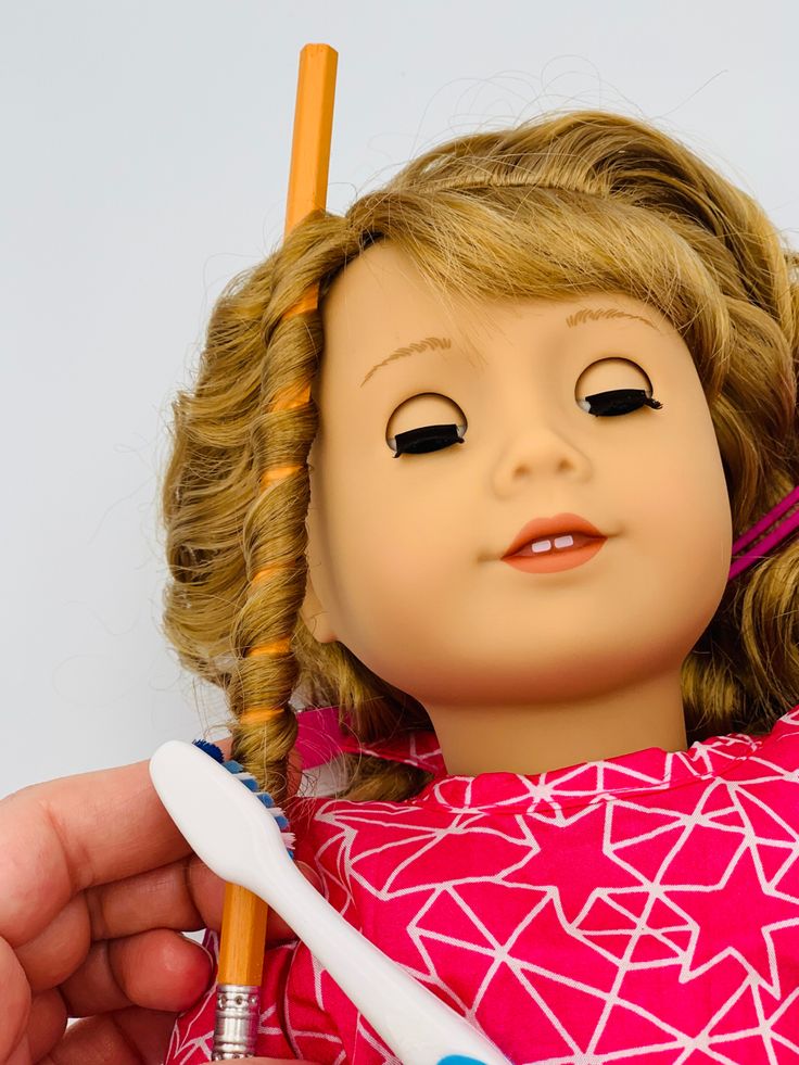 a close up of a doll holding a toothbrush