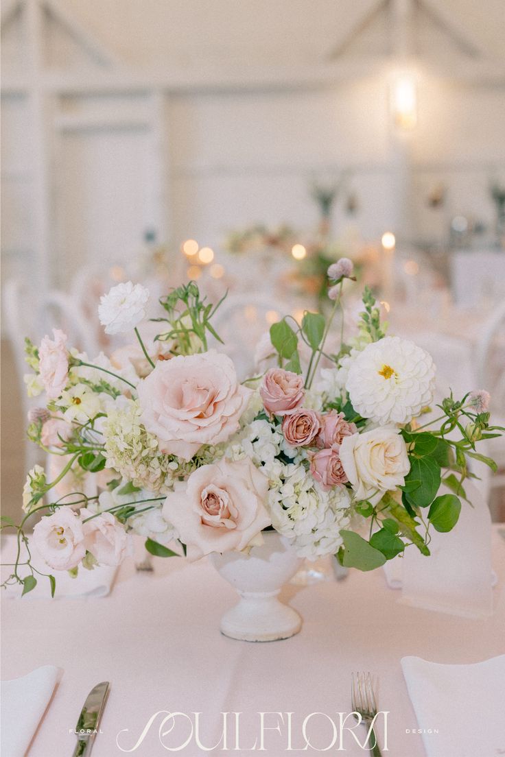 a vase filled with lots of flowers on top of a white table cloth covered table