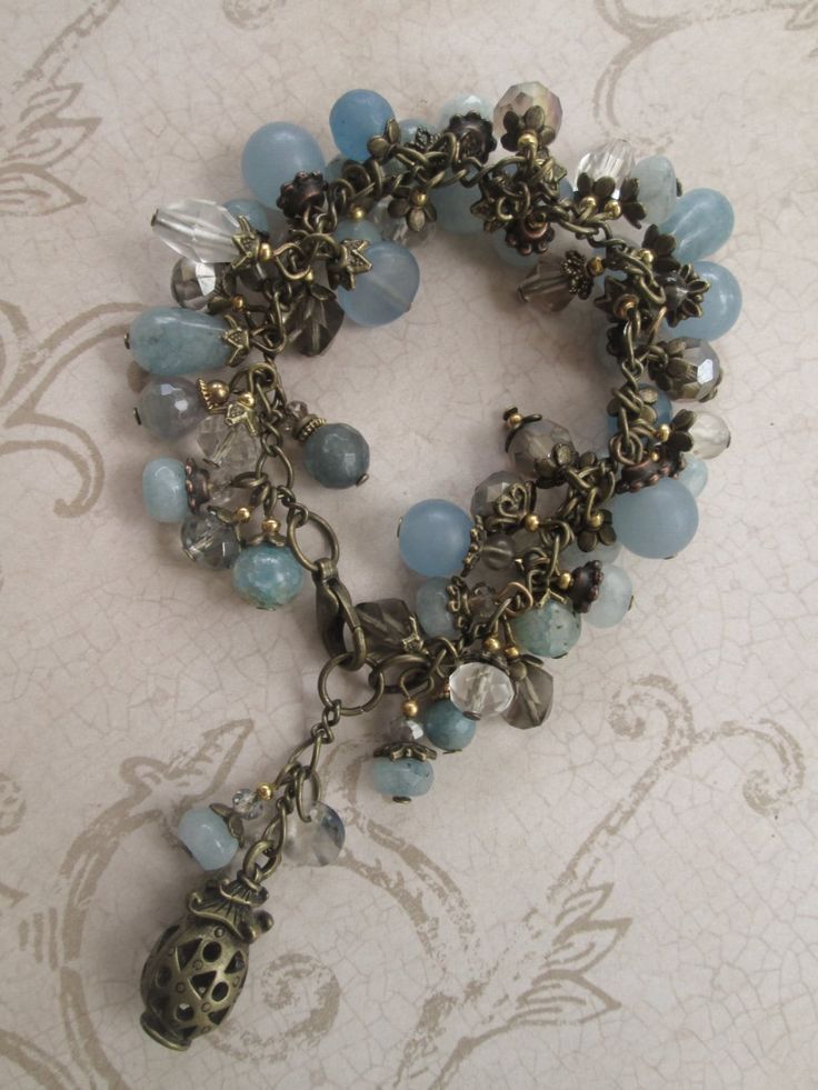 "Brazilian Aquamarine beads in teardrop, rondelle, faceted, coin and round-shaped in different hues of blue are combined with faceted Quartz, Dragon Veins Agate and Swarovski crystals.  An antique gold lantern charm dangles near the lobster claw closure.   The bracelet measures 6 1/2 \" long, extendable to 7\" with the existing chain.  If you need the bracelet extended/shortened, I will so so at no additional cost; just send me your desired length." Antique Charm Bracelet, Wired Jewelry, Beaded Jewels, Beads Bracelet Design, Aquamarine Beads, Assemblage Jewelry, Chunky Bracelets, Wire Work Jewelry, Handmade Wire Jewelry