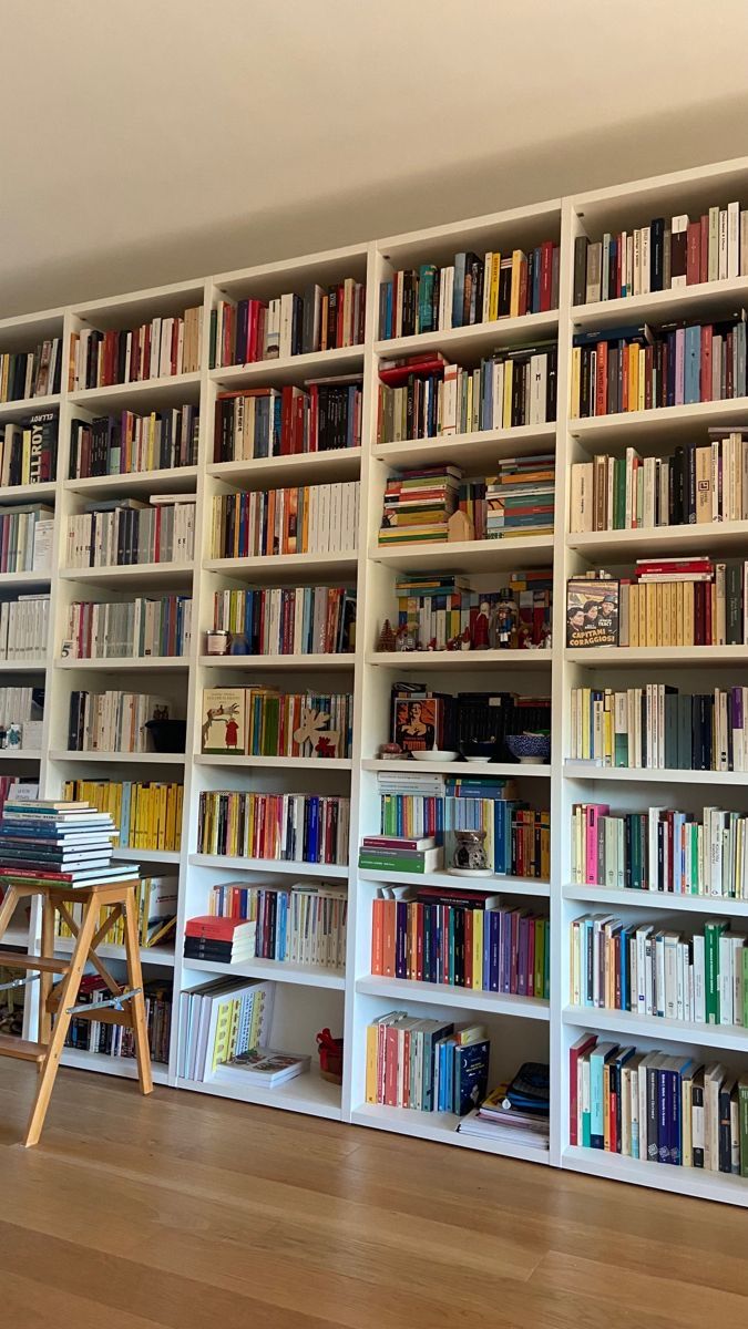 a bookshelf filled with lots of books on top of a hard wood floor