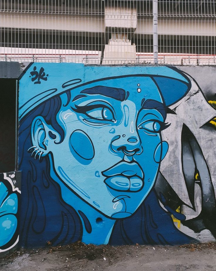 a blue and black mural on the side of a building with a woman's face