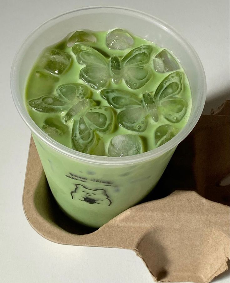 a cup filled with green liquid on top of a table