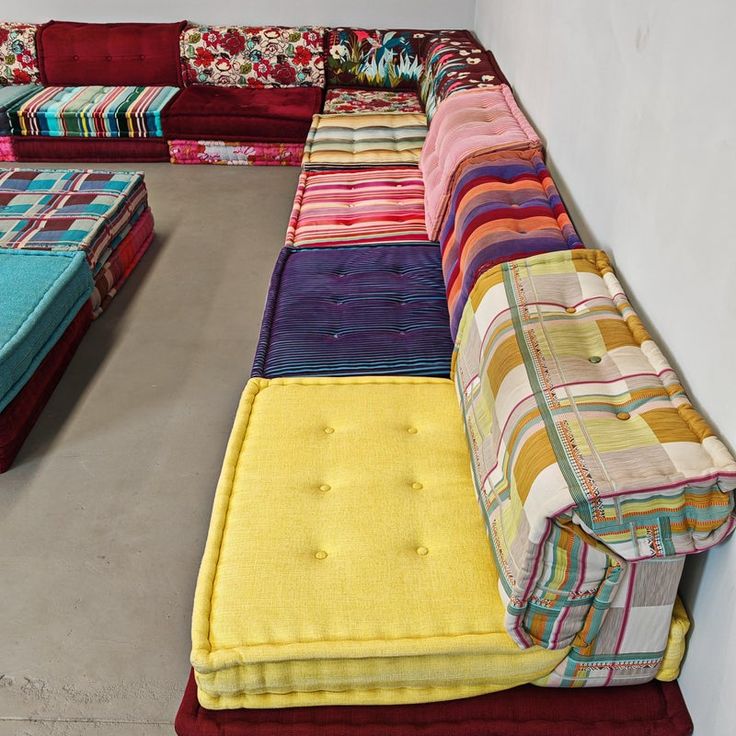 a multicolored patchwork couch sitting on top of a cement floor