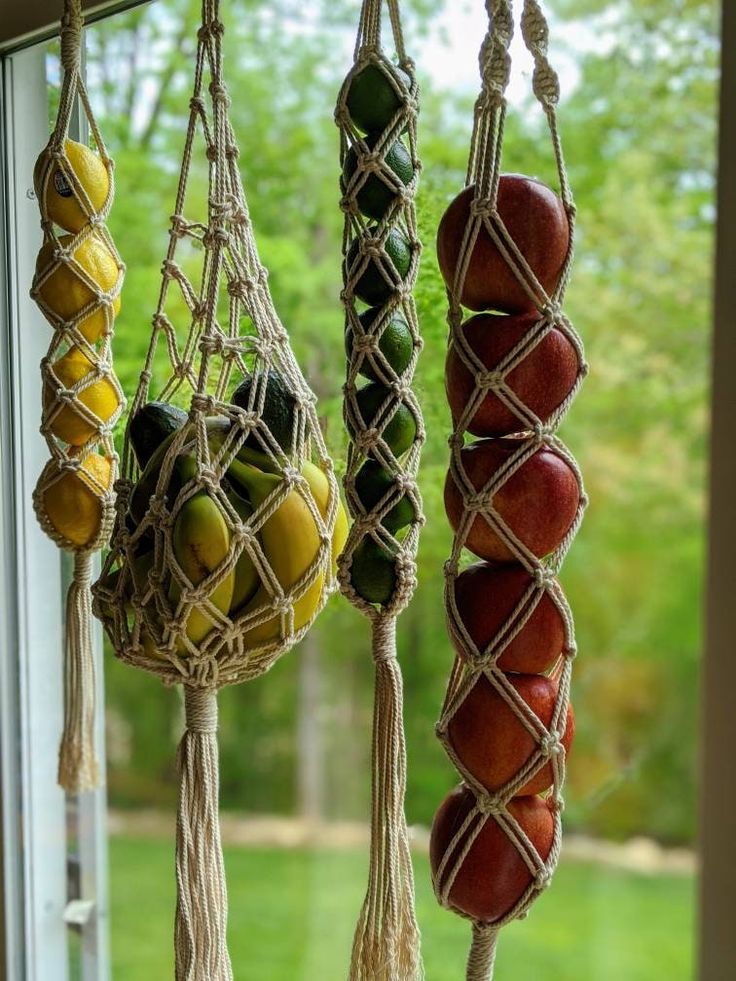 several hanging fruit baskets in front of a window with trees outside the window behind them