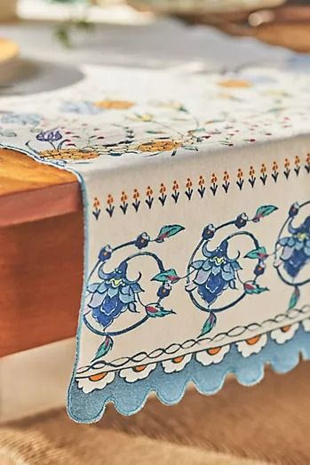 the table is covered with blue and white embroidered linens, along with other decorative items