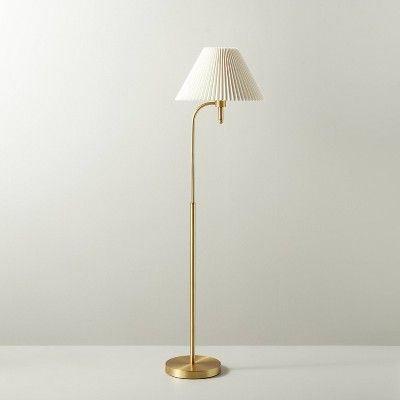 a floor lamp with a white shade on the base and a gold plated metal base