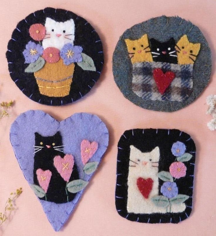 four felt heart shaped magnets with cats and flowers in them on a pink background