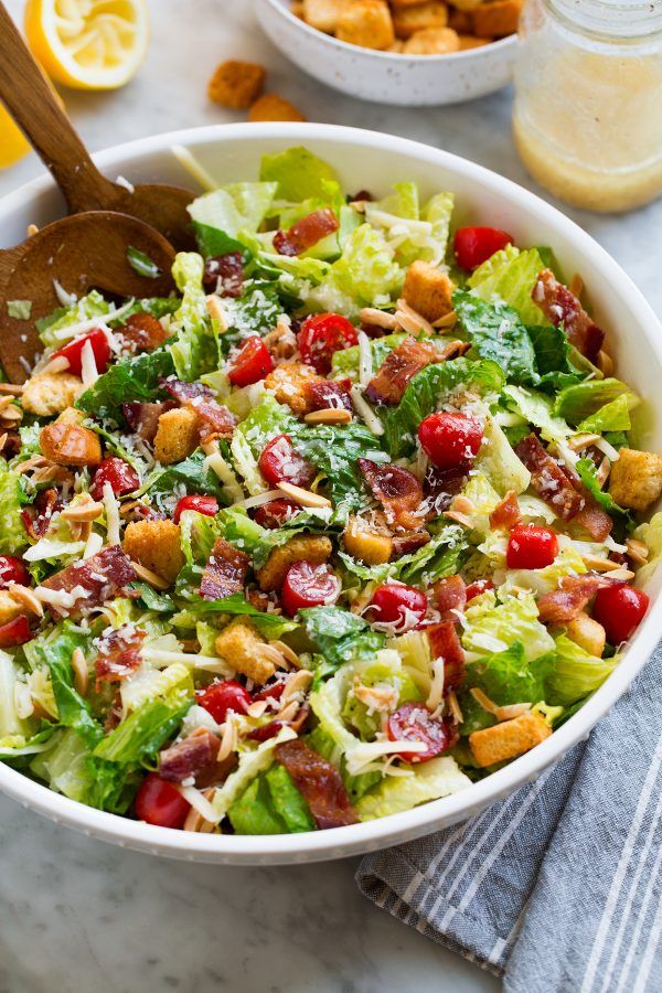 a salad with lettuce, cranberries and nuts in a white bowl