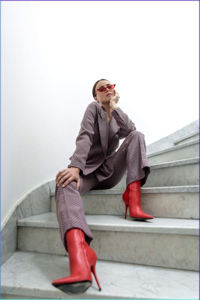 a woman sitting on some steps talking on a cell phone and wearing red high heels