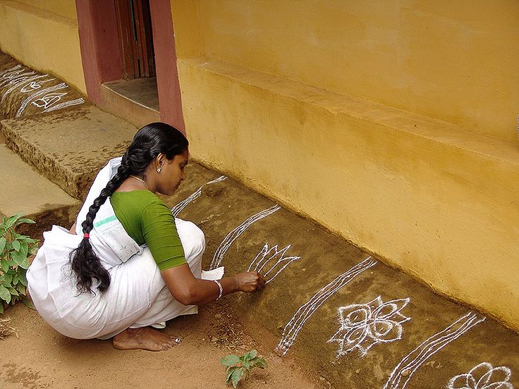 a woman kneeling down on the ground drawing something with white chalk and green marker paint