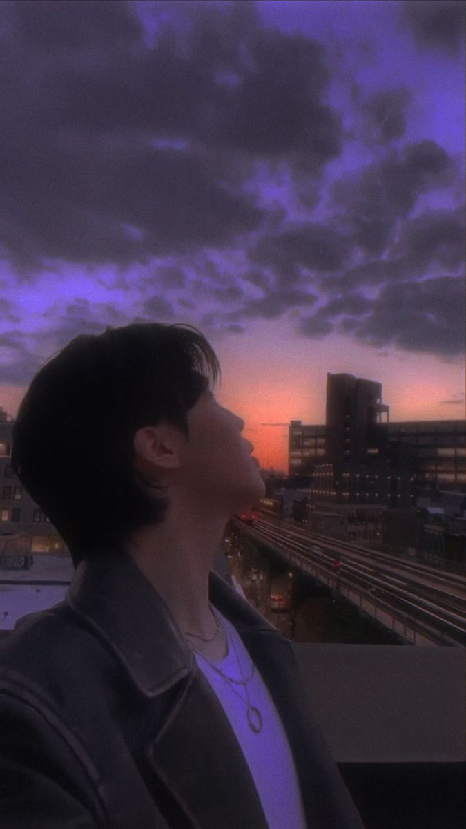 a man standing on top of a roof next to a tall building under a cloudy sky