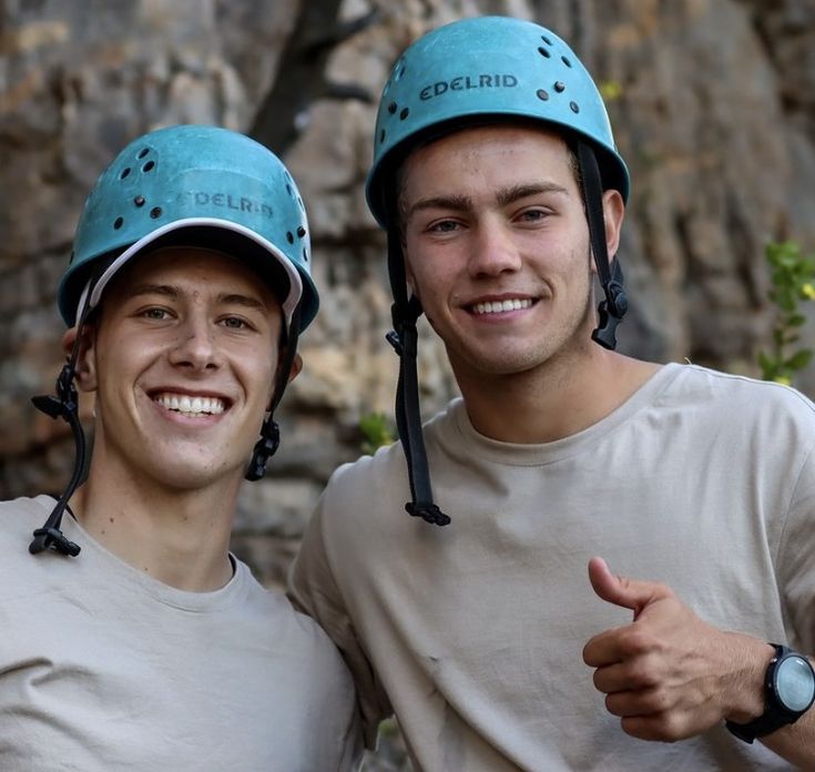 two young men wearing helmets giving the thumbs up