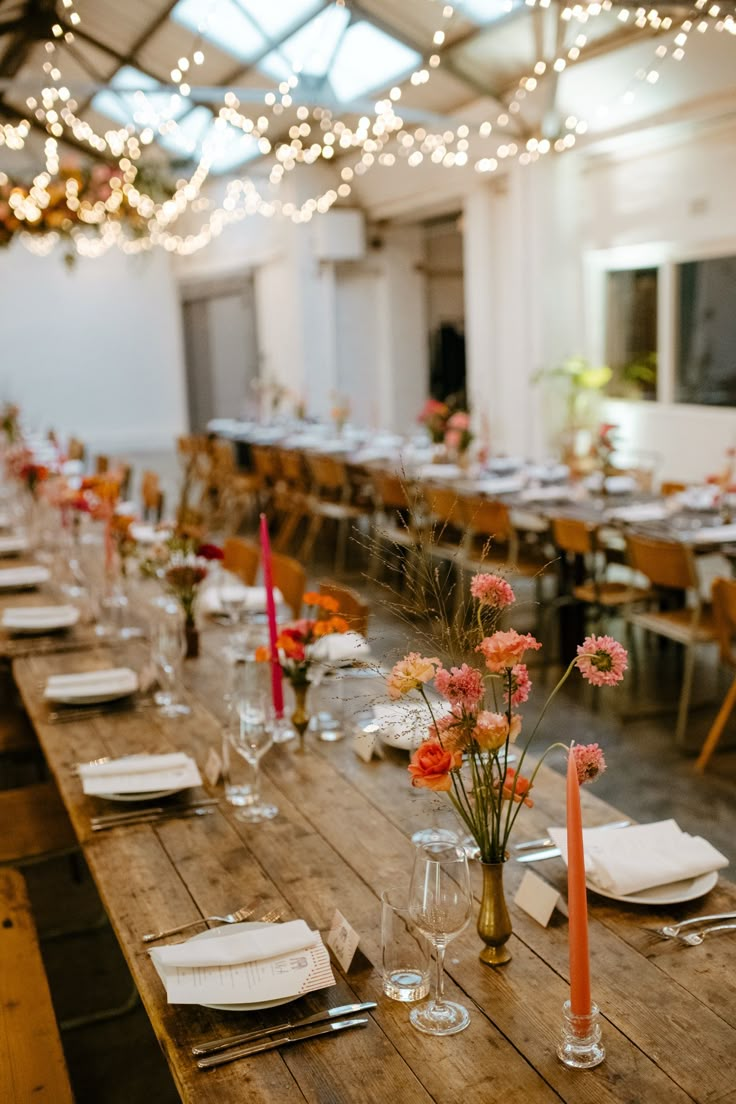 the long table is set with place settings and flowers in vases on each side