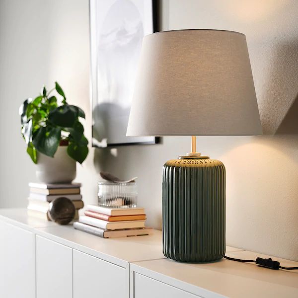 a green lamp sitting on top of a white dresser